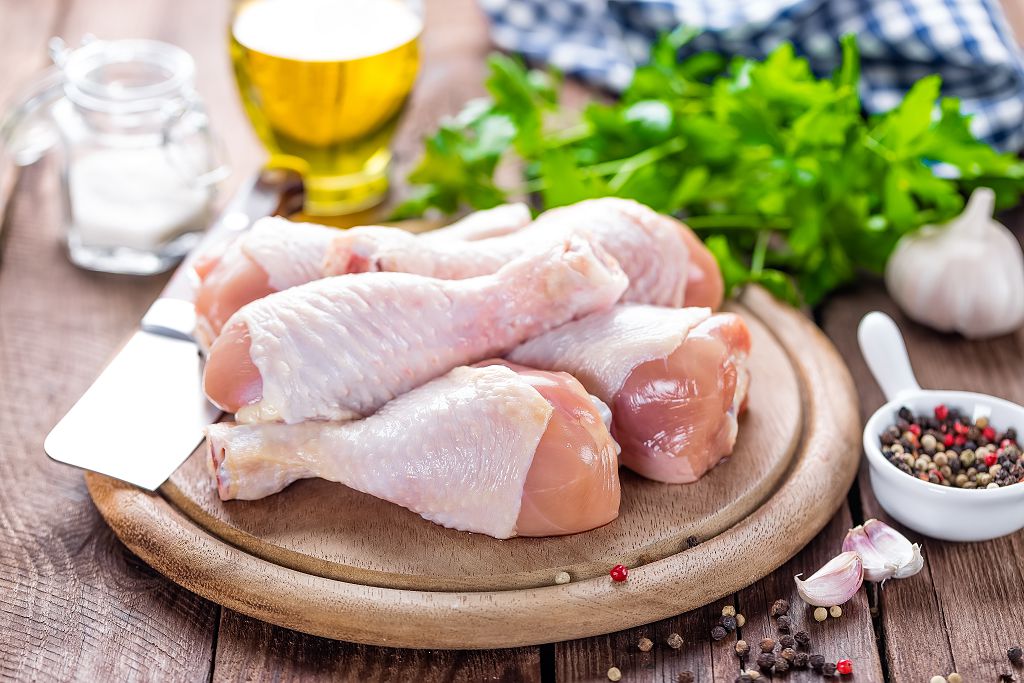  Cuisses de poulet fraîches et un couteau sur des planches à découper, des herbes et des légumes